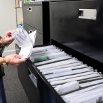 Hands of local Florida staff sifting through files and mail.