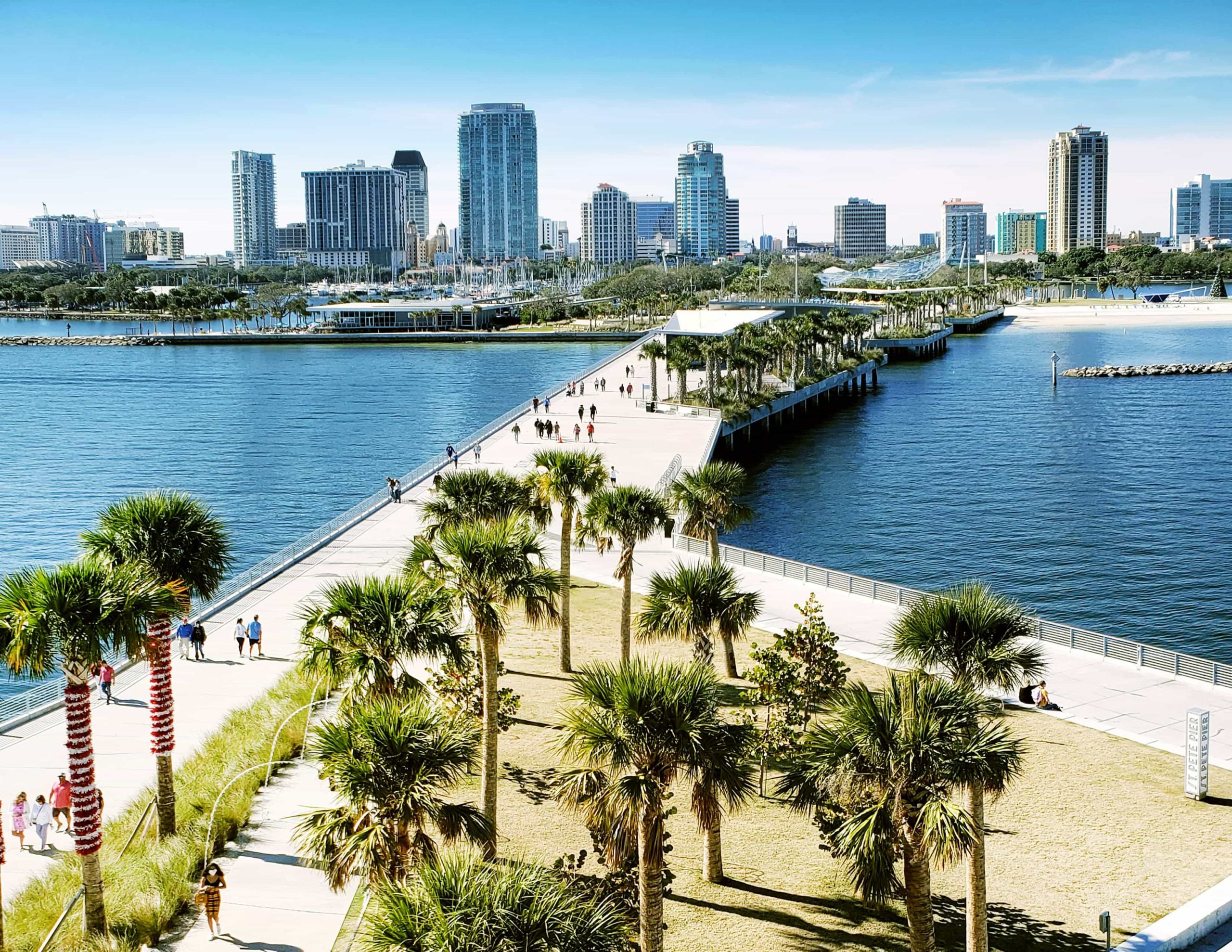 Birdeye view of people walking on the St. Petersburg pier with a view of downtown in the background.