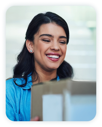 Woman smiling and carrying a cardboard box.