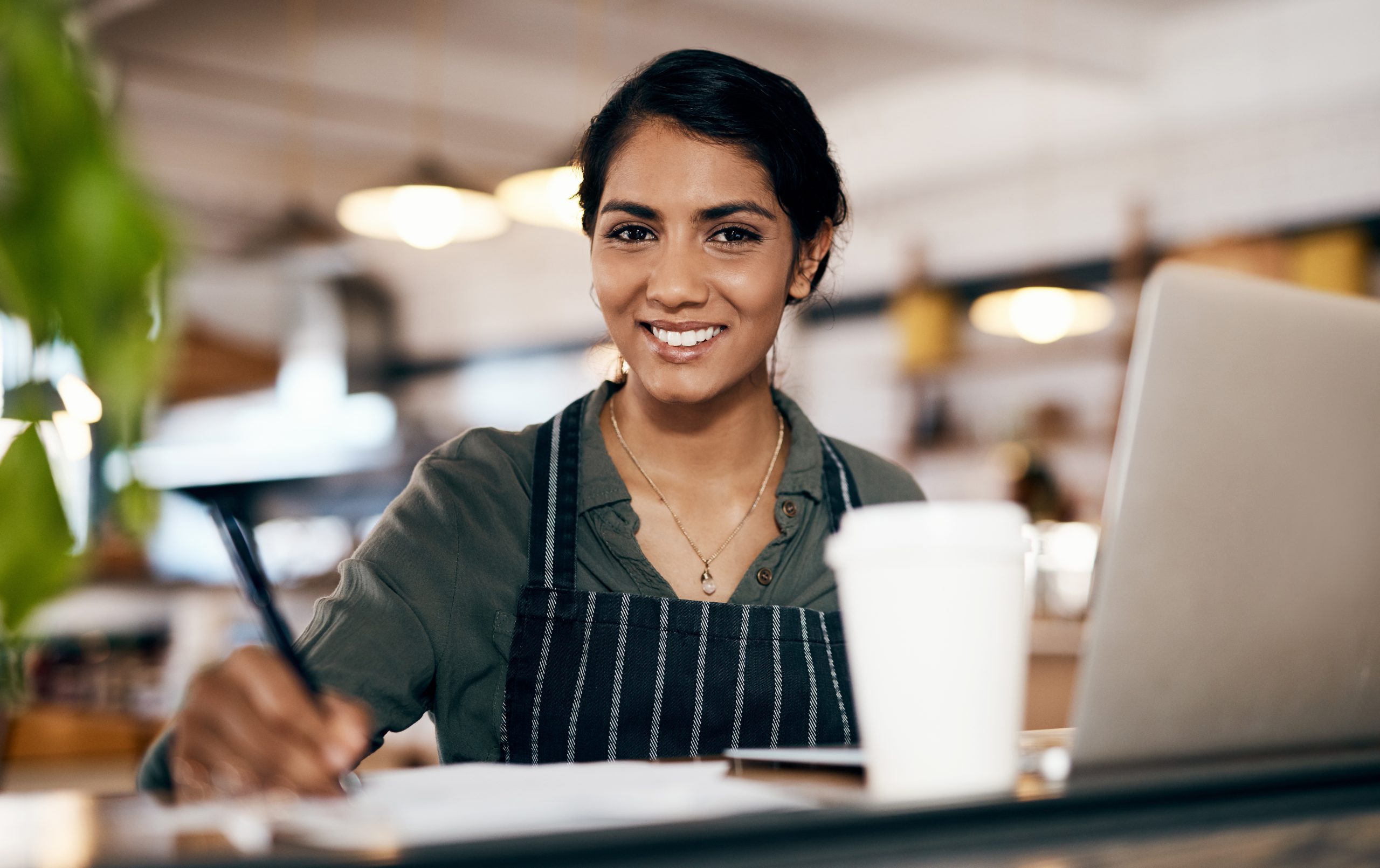 Cafe owner, laptop or portrait with documents for coffee shop website, financial tracking or profit accounting. Happy, paperwork or technology for small business woman in restaurant for bakery sales.